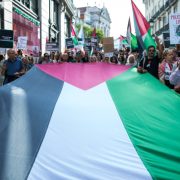 Imagem de várias pessoas a segurarem uma bandeira XL da Palestina, durante uma manifestação em Lisboa
